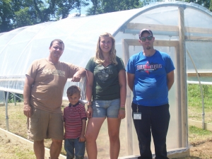Mark, the second youngest Wolf child, Lindsey Harper, and Chad Brock, standing in front of a completed high tunnel!