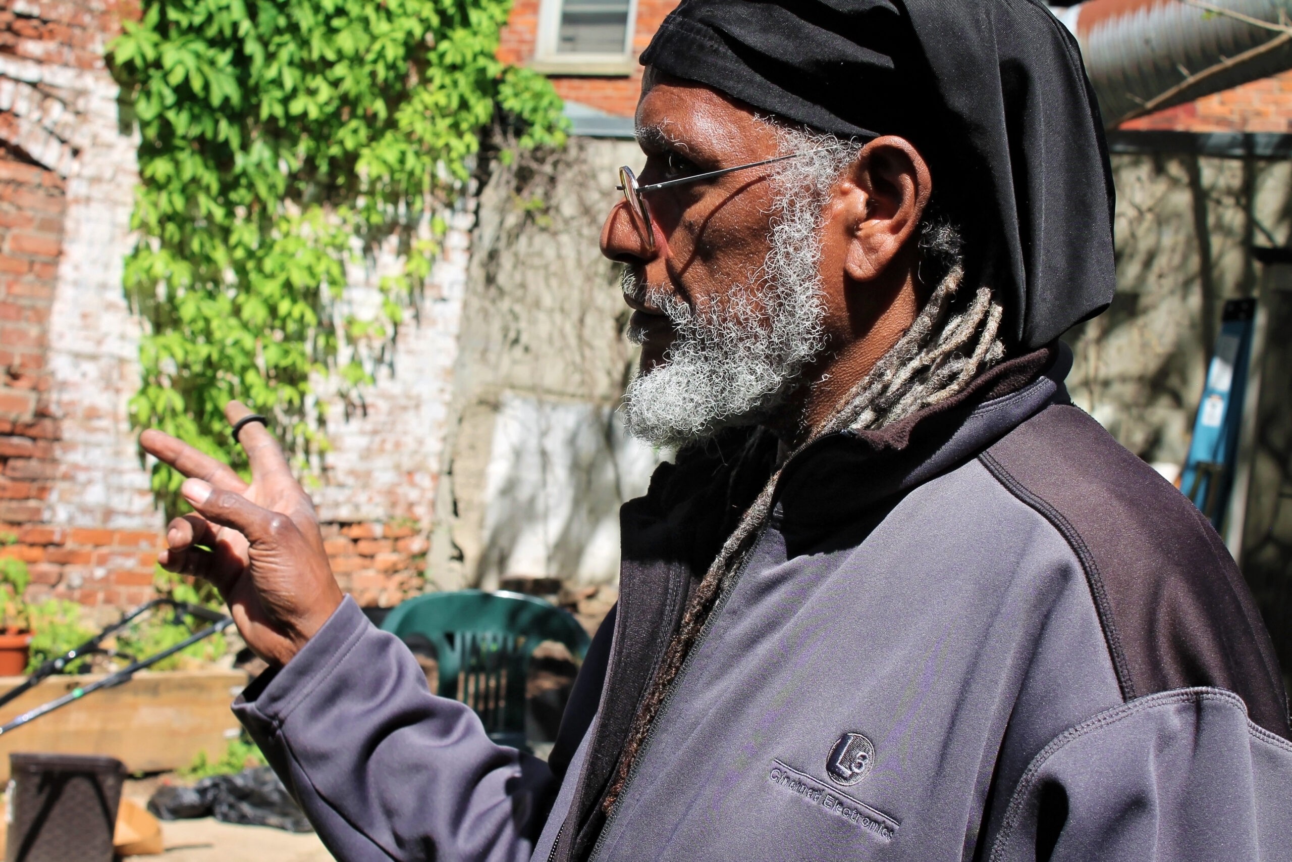 A man with a beard points at raised garden beds.