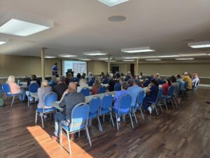 The image shows a large gathering of Grow Appalachia members at their monthly meeting.