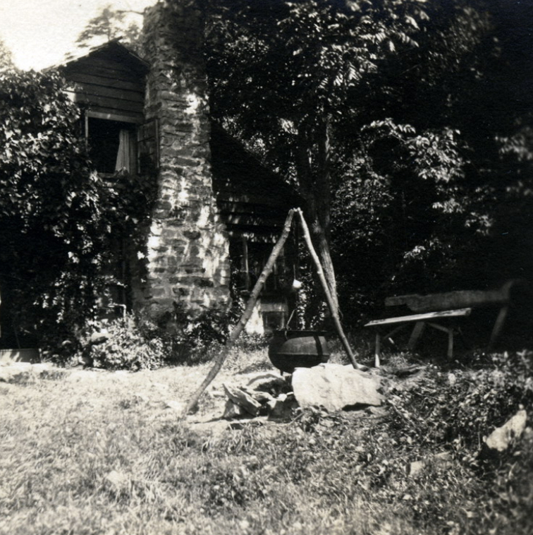 Dye pot on tripod outside Katherine Pettit’s residence (Big Log), Undated